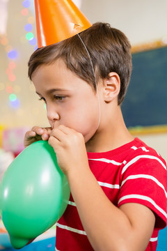 生日派对上吹气球的可爱男孩