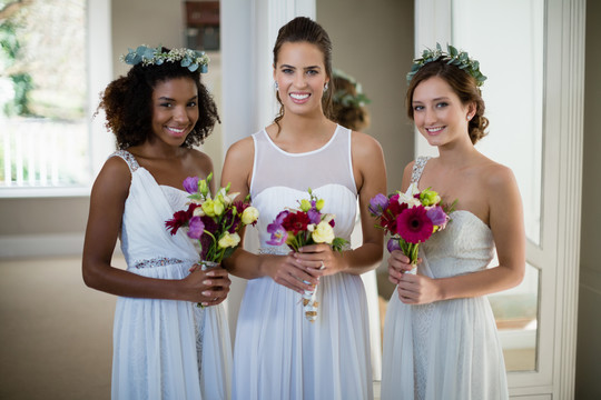 新娘和伴娘站在家里捧着花束