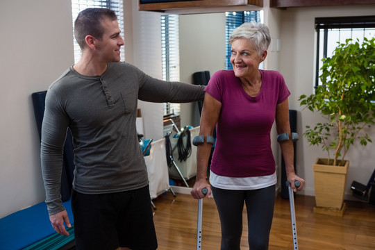理疗师帮老年女性患者用拐杖行走