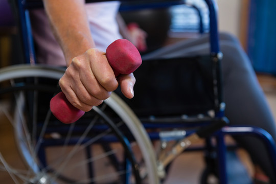 坐轮椅的老年妇女用哑铃做运动
