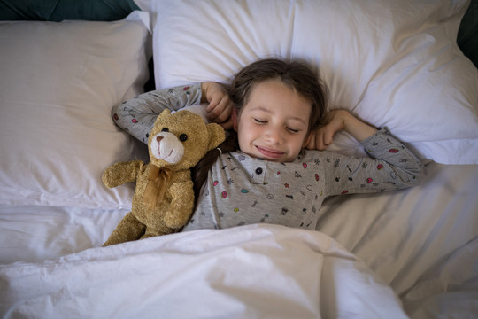 卧室里的抱着泰迪熊的小女孩