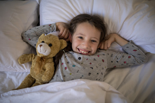 躺在床上抱着玩具熊的女孩