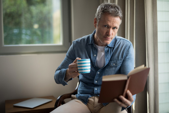 在客厅喝咖啡的时候看书的男人