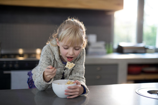 小女孩用碗里的勺子吃五谷圈