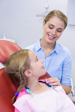 微笑的母亲在牙科诊所给女儿刷牙