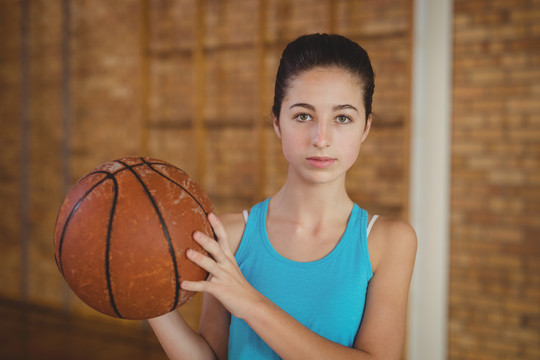 球场上抱着篮球的坚定女孩的肖像