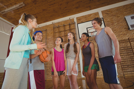 女教练在篮球场指导高中生