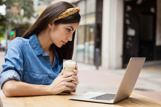 女人在路边咖啡厅用笔记本电脑