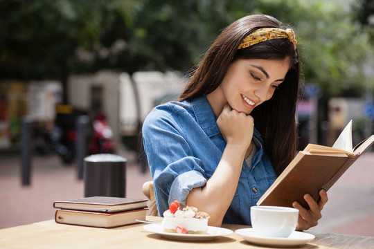 坐在路边咖啡馆边读书边的女人