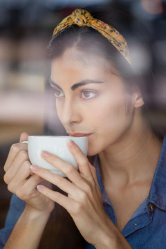 在喝咖啡的时候看着远处的女人
