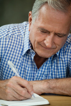 老年人在餐桌上写日记的特写
