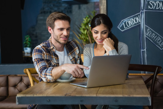年轻夫妇在咖啡馆使用笔记本电脑