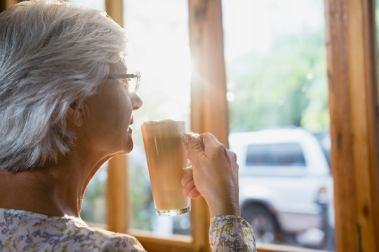 体贴的老年妇女喝咖啡