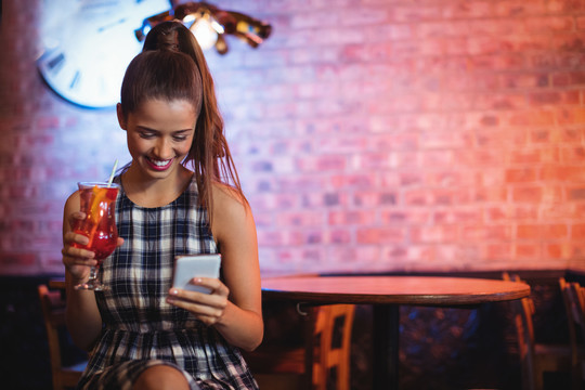 酒吧中使用手机的年轻女子