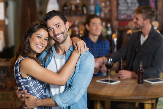 微笑的年轻夫妇在酒吧拥抱