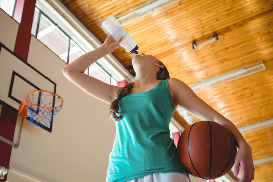 女子站在篮球场喝水
