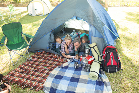 一家人在营地帐篷里看摄像机