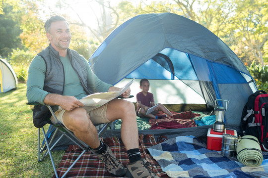 微笑的男人在营地帐篷外看地图