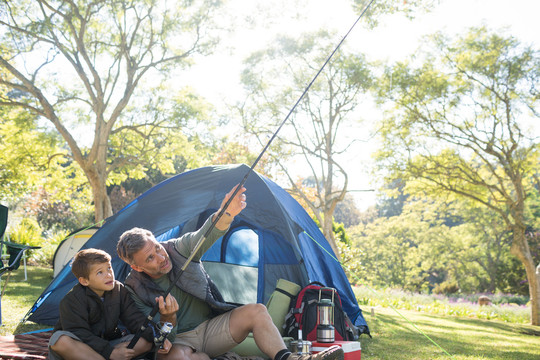 爸爸和儿子在帐篷外拿着鱼竿