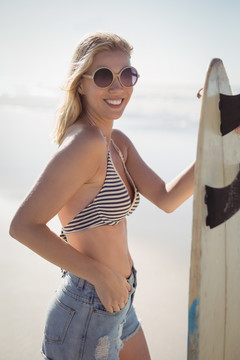 海滩上拿着冲浪板的年轻女性