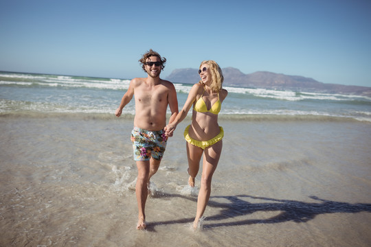 快乐的年轻夫妇在海滩上奔跑