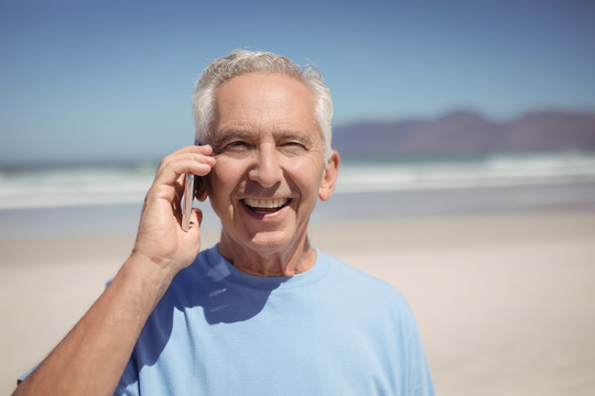 海滩上讲手机的老人的照片