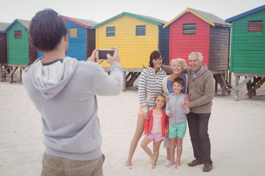 站在海滩上拍家庭照片的男人