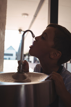 口渴的男孩从学校的水龙头里喝水
