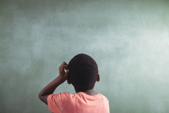 体贴的男孩站在教室的黑板前