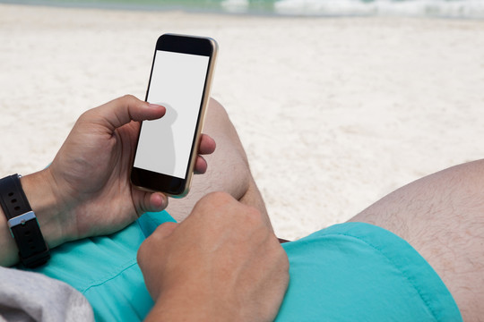 在海滩的椅子上休息时使用手机