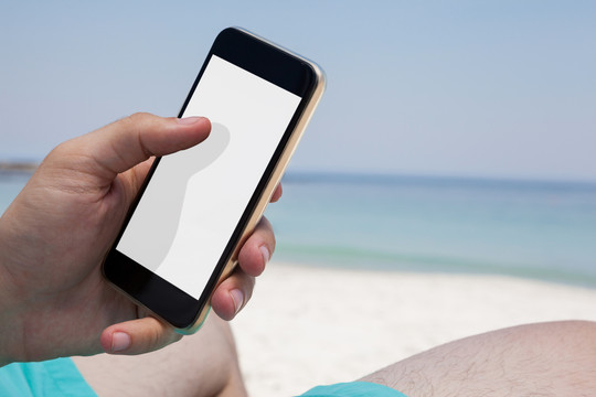 在海滩的椅子上休息时使用手机