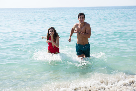快乐的年轻夫妇在海边沙滩上奔跑
