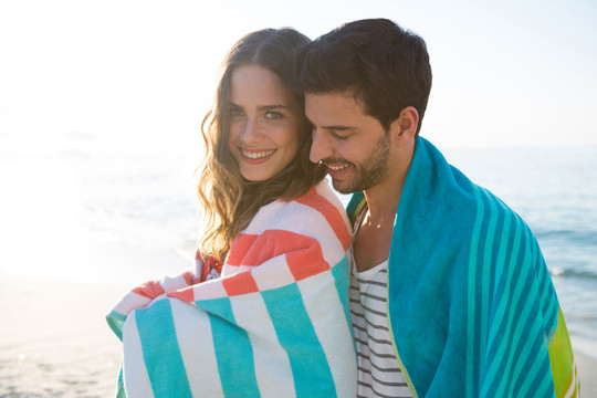 海滩上裹着毯子的幸福年轻夫妇