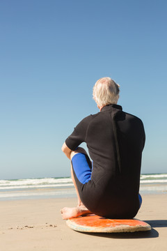 沙滩上站在冲浪板上的老人