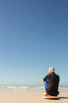沙滩上站在冲浪板上的老人