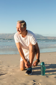 笑容满面的老人在沙滩上系鞋带