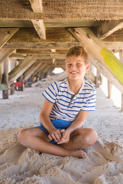 在海滩小屋下玩沙的男孩的肖像