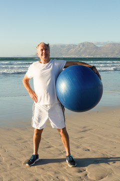 在沙滩上举健身球的老人