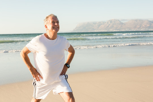 微笑的老人站在沙滩上锻炼身体