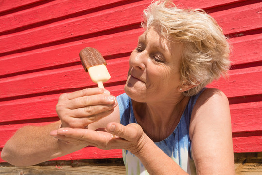 老太太站在海滩小屋边吃冰淇淋