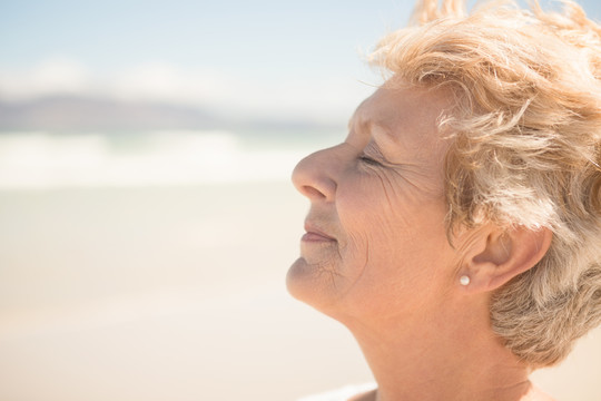 在海滩上闭上眼睛放松的老妇人