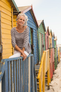 坐在海滩小屋栏杆上微笑的老妇人