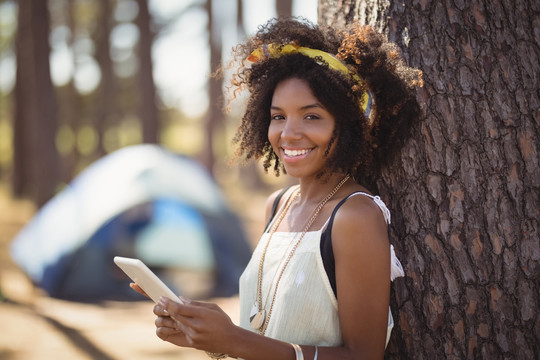 快乐女孩站在帐篷旁用智能手机