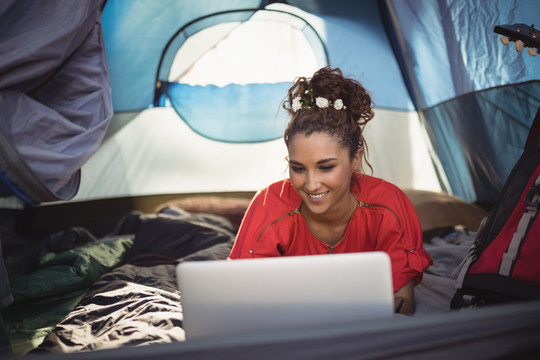 躺在帐篷里用笔记本电脑的女子