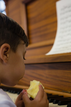 男孩靠着钢琴吃苹果的特写镜头