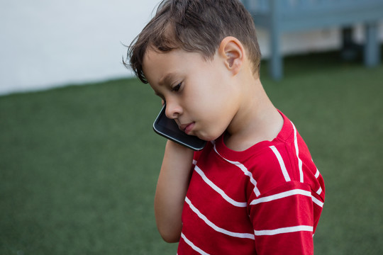 男孩站在学校场地上用手机说话