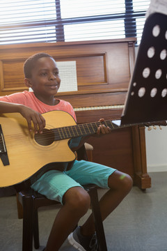 快乐的男孩坐在教室里弹吉他