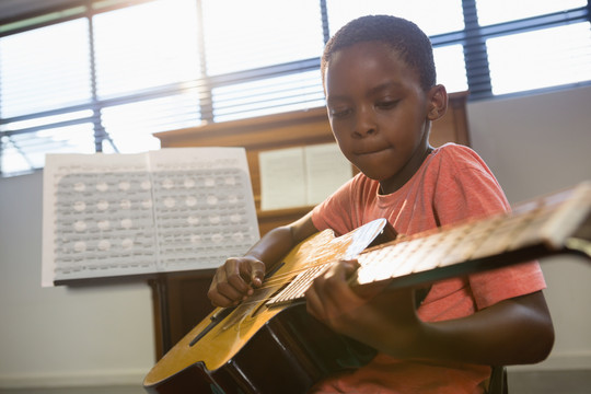 在音乐学校上课弹吉他的男孩