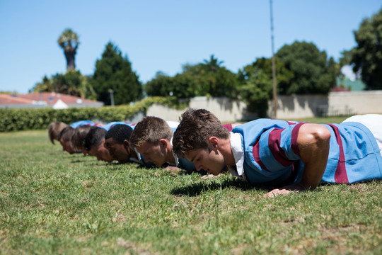 橄榄球运动员在草地上做俯卧撑