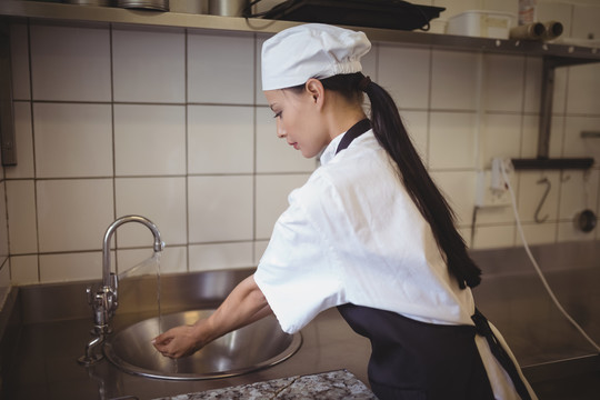 女厨师在餐厅的商业厨房洗手